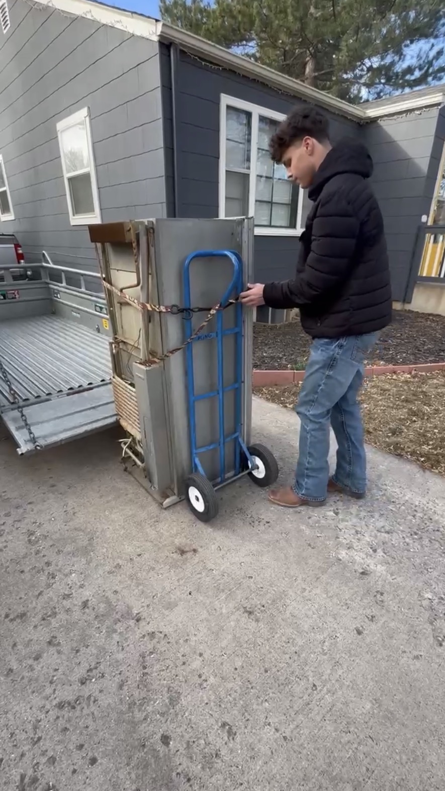 Connor hauling a fridge on a dolly for junk removal in Northern Colorado